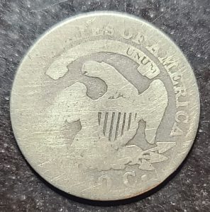 Silver coin with eagle and shield design on a dark surface