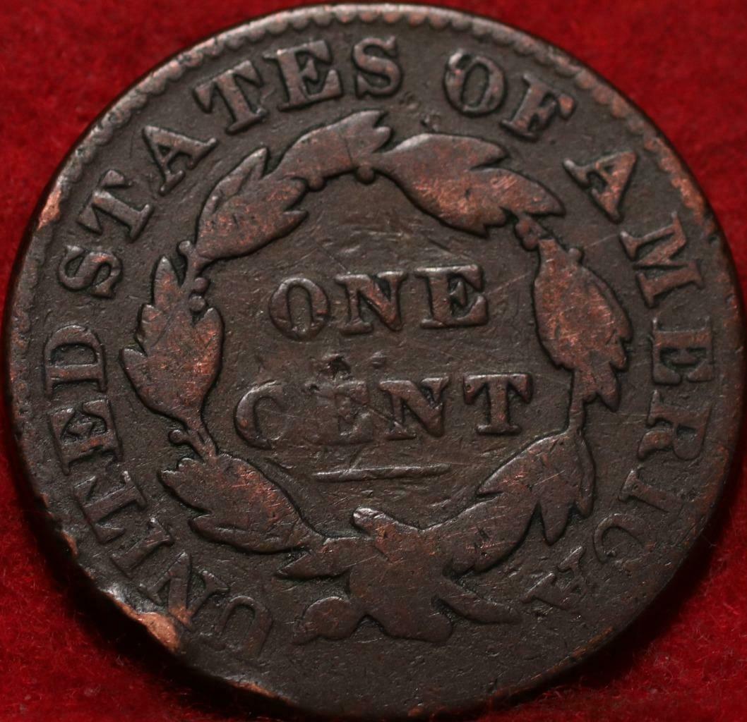 Old copper coin with 'United States of America' and 'One Cent' text on a red background
