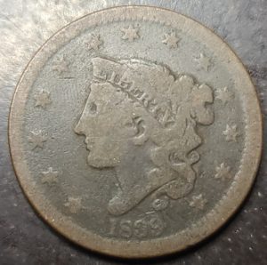 Vintage coin with a profile of a person and star design on a dark background