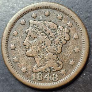 Vintage copper coin with a profile of a person and the year 1848 on a dark background