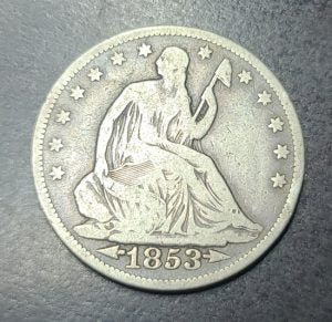 Silver coin with '1853' on a dark background
