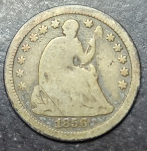 Vintage coin with '1856' marking on a dark background