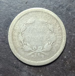 Silver coin with a wreath design on a dark surface