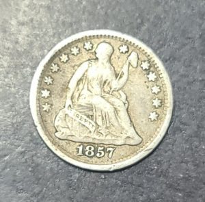 Vintage silver coin with '1857' on a gray background