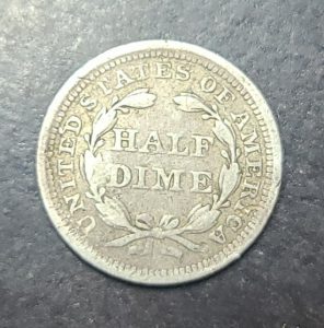 Silver half dime coin on a dark surface