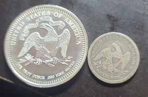 Two silver coins with embossed designs on a dark surface