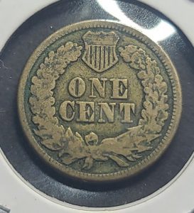 Vintage one cent coin with a shield design on a reflective surface