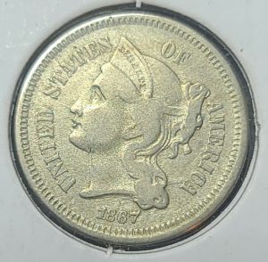 A close up of a 1867 3 cent nickel 