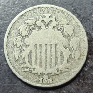 A close up of an 1868 shield nickel 