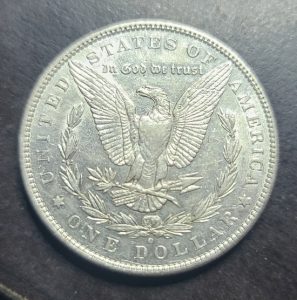 Silver dollar coin with an eagle emblem on a dark background