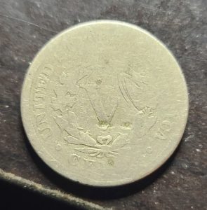 Metallic coin with embossed design on a dark surface