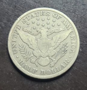 Silver half dollar coin with detailed design on a dark background