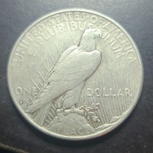 Silver dollar coin with an eagle design on a dark background
