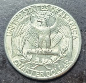 Silver quarter dollar coin with an eagle emblem on a dark background
