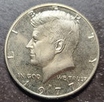 U.S. half dollar with Kennedy's profile and 'In God We Trust' inscription.