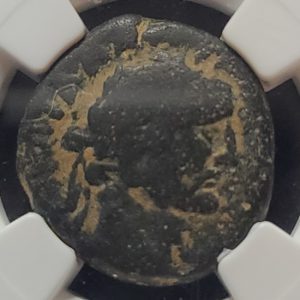 Ancient coin with gold embellishments under a magnifying glass