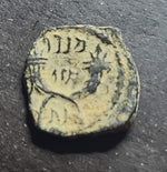 Ancient coin with inscriptions on a dark surface