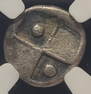Close-up of a metallic coin with a cross design on a white background